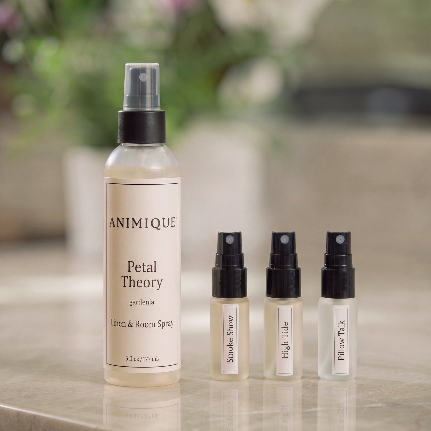 One full size and three discovery bottles of Animique pet-safe linen and room spray on a marble countertop