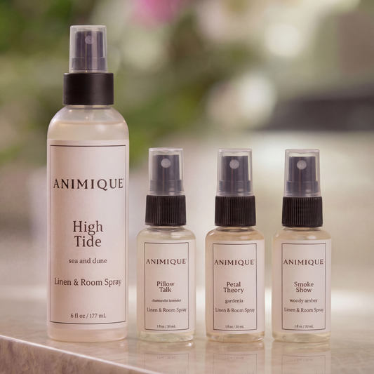 One full-size and three-sample size bottles of Animique pet-safe linen and room spray on a marble countertop.