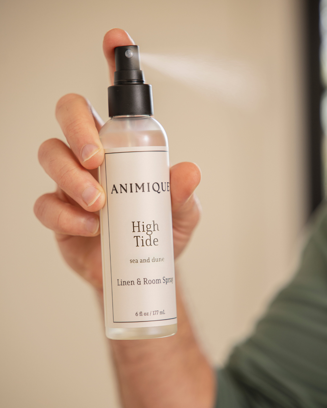 High Tide room and linen spray by Animique — pet-safe home fragrance being sprayed by a man's hand