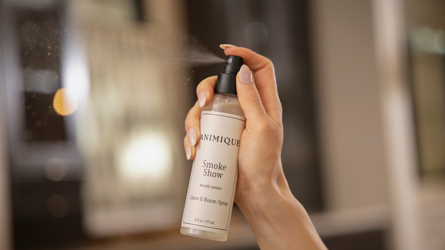 Hand holding a bottle of Animique Smoke Show product with a blurred background